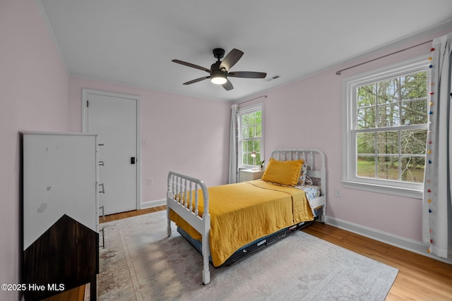 bedroom with baseboards, a ceiling fan, wood finished floors, and visible vents