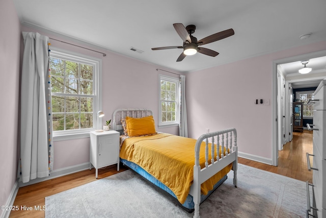 bedroom with baseboards, wood finished floors, and visible vents