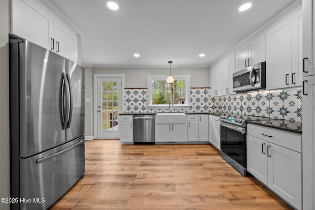 kitchen featuring a sink, white cabinets, dark countertops, and stainless steel appliances