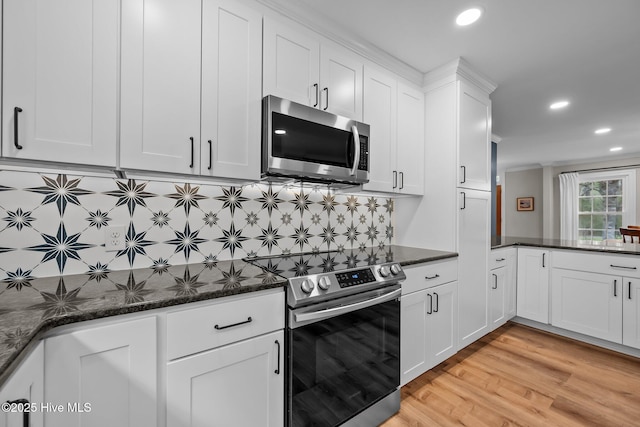 kitchen featuring recessed lighting, dark stone counters, white cabinets, appliances with stainless steel finishes, and backsplash