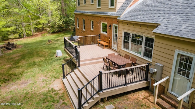 wooden terrace with a lawn, outdoor dining space, and entry steps