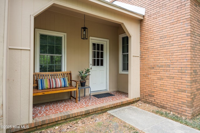 view of exterior entry featuring brick siding and covered porch