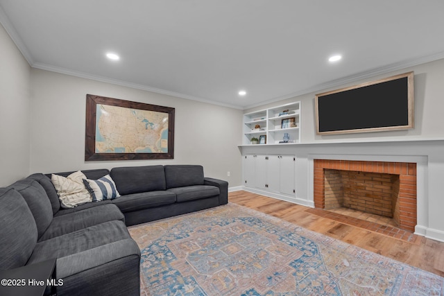 living room featuring light wood finished floors, a fireplace, built in shelves, baseboards, and ornamental molding