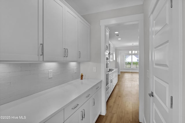 4434 Old Towne St, Wilmington, NC 28412 - kitchen featuring white cabinetry, light wood finished floors, decorative backsplash, recessed lighting, and a chandelier