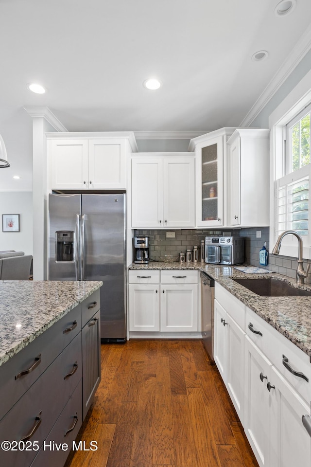 6460 Carrick Bend Trl SW, Ocean Isle Beach, NC 28469 - kitchen featuring stainless steel appliances, ornamental molding, white cabinets, glass insert cabinets, and light stone countertops