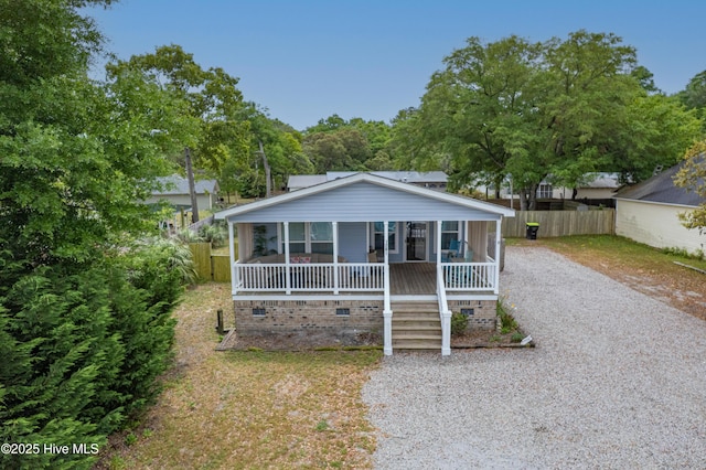bungalow-style home with driveway, crawl space, covered porch, and fence