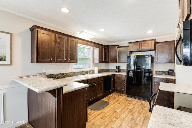 kitchen with black appliances, dark brown cabinets, light wood finished floors, a sink, and a peninsula