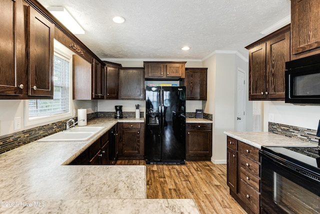 kitchen with wood finished floors, black appliances, dark brown cabinets, ornamental molding, and a sink