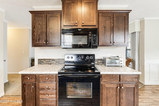 kitchen with crown molding, light countertops, black appliances, a toaster, and light wood finished floors
