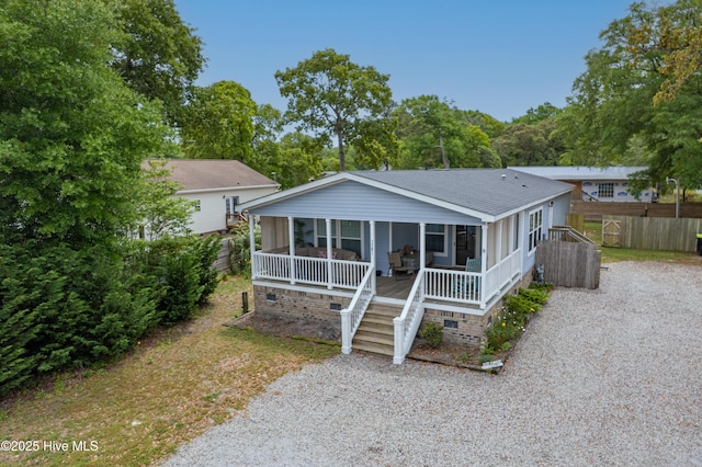 bungalow-style home with a sunroom, crawl space, a shingled roof, gravel driveway, and fence