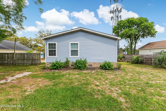 rear view of house with crawl space, a yard, and fence