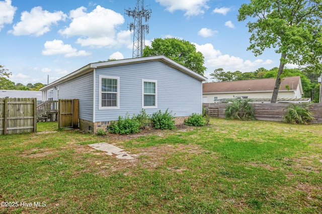 rear view of property featuring a lawn and fence