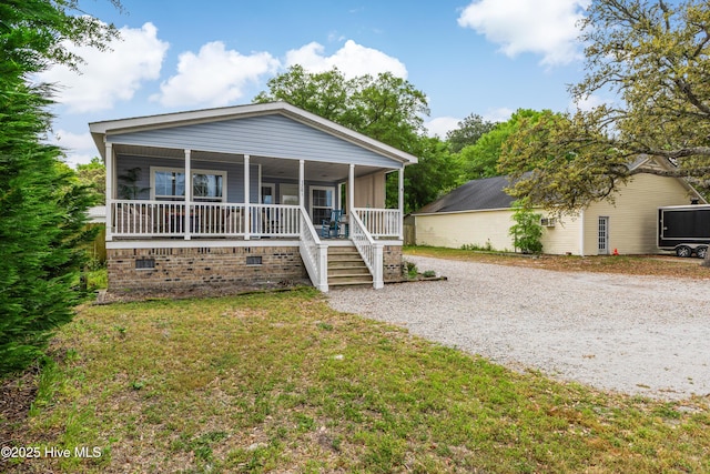view of front facade featuring covered porch, gravel driveway, a front lawn, and crawl space