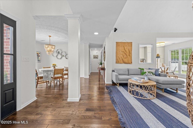 living room with dark wood finished floors, decorative columns, baseboards, and a chandelier