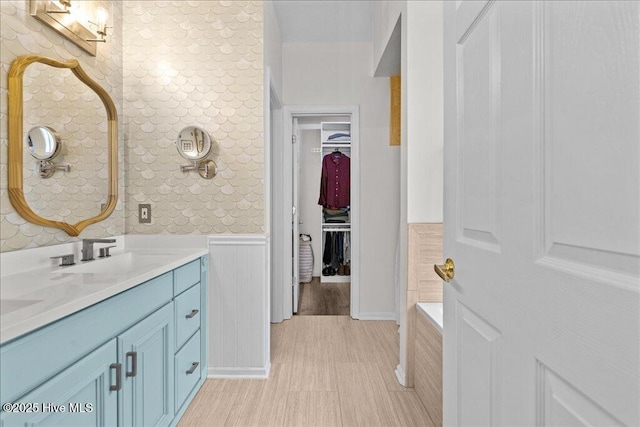 bathroom featuring wainscoting, a spacious closet, and double vanity