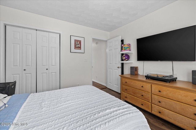 bedroom featuring a closet, dark wood-type flooring, and baseboards