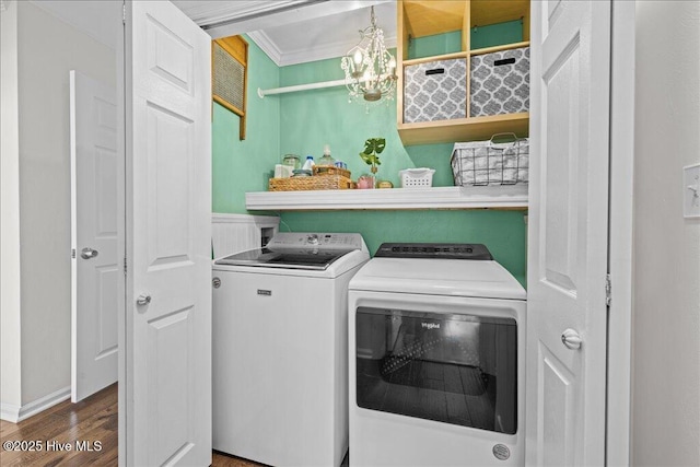 clothes washing area with washing machine and dryer, wood finished floors, ornamental molding, and a chandelier