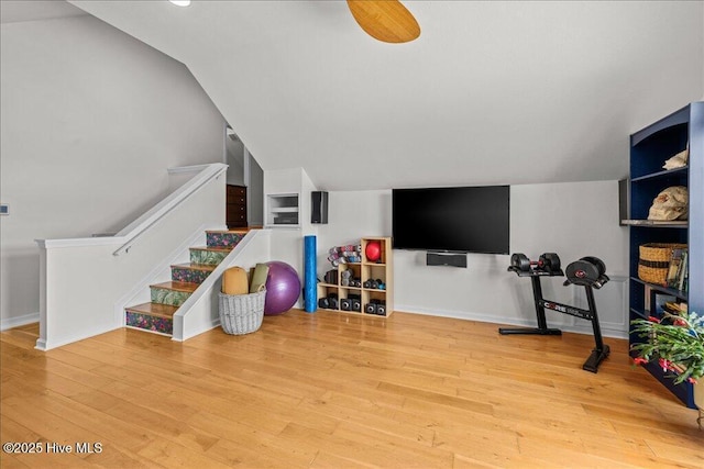 workout area featuring hardwood / wood-style floors, vaulted ceiling, and baseboards
