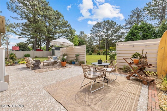 view of patio with outdoor dining space, a fenced backyard, a storage unit, and an outdoor structure
