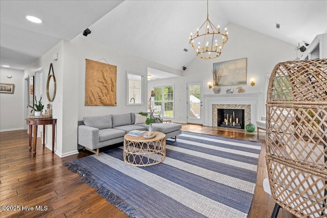 living area featuring wood-type flooring, baseboards, a fireplace with flush hearth, high vaulted ceiling, and a chandelier