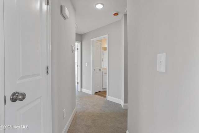 corridor featuring baseboards and carpet flooring