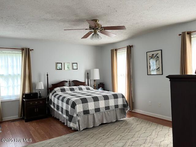 bedroom with a textured ceiling, multiple windows, and wood finished floors