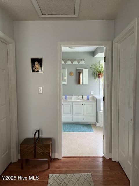 interior space with baseboards, a sink, wood finished floors, and attic access