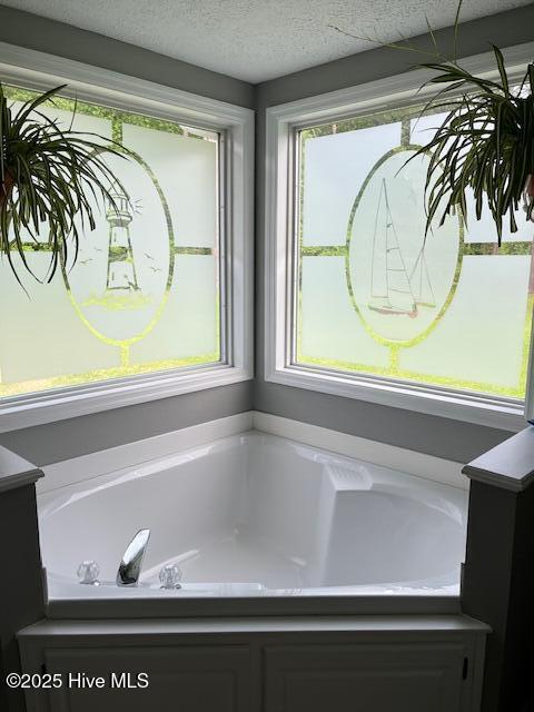 full bath featuring a textured ceiling and a garden tub