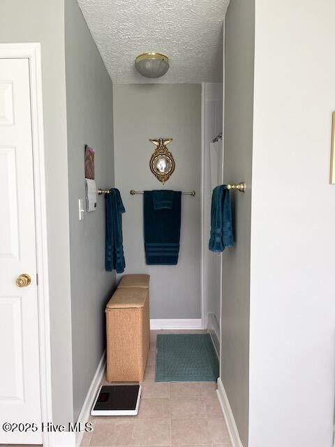 mudroom with tile patterned floors, baseboards, and a textured ceiling