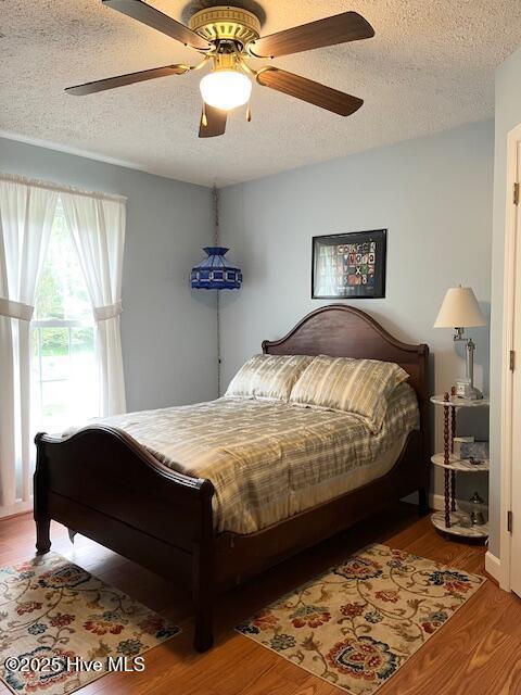 bedroom featuring a ceiling fan, a textured ceiling, and wood finished floors