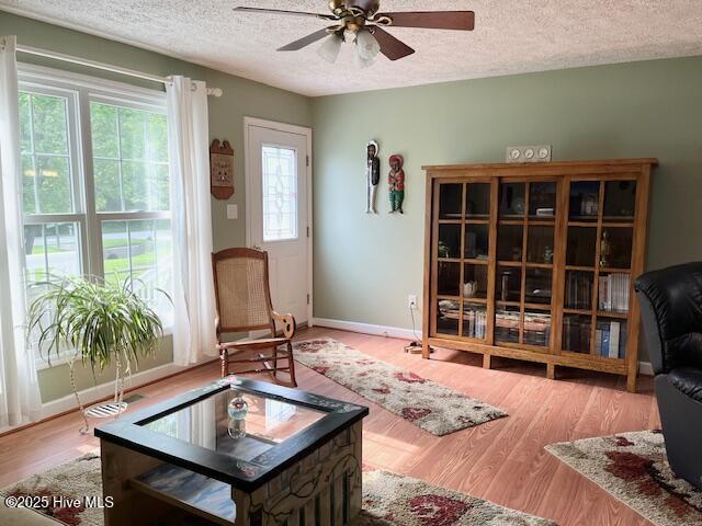 sitting room featuring baseboards, a textured ceiling, ceiling fan, and wood finished floors