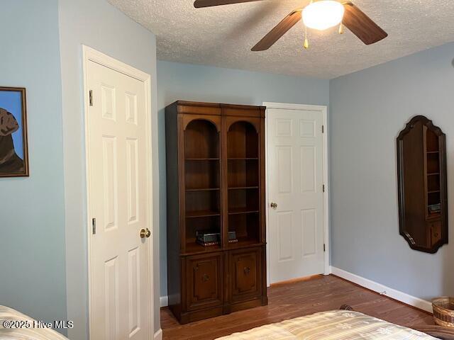 unfurnished bedroom with baseboards, ceiling fan, a textured ceiling, and wood finished floors