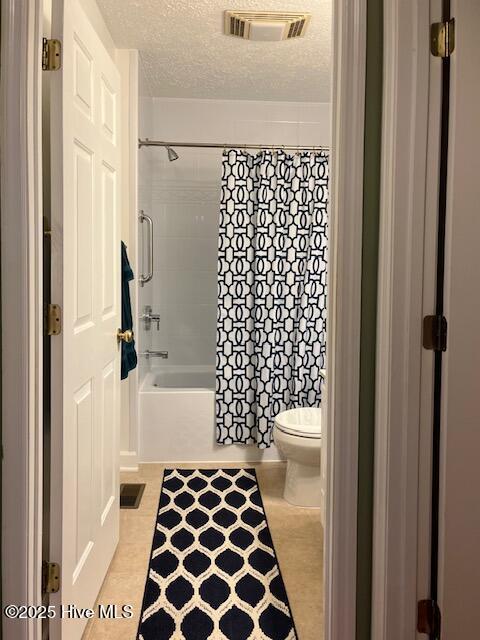 bathroom with shower / bath combo, toilet, a textured ceiling, and visible vents