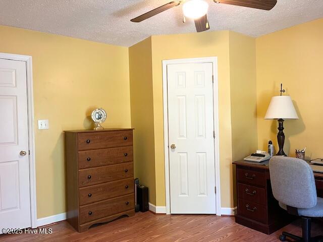 office area featuring baseboards, a textured ceiling, ceiling fan, and wood finished floors