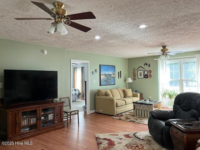 living area featuring a textured ceiling, ceiling fan, and wood finished floors