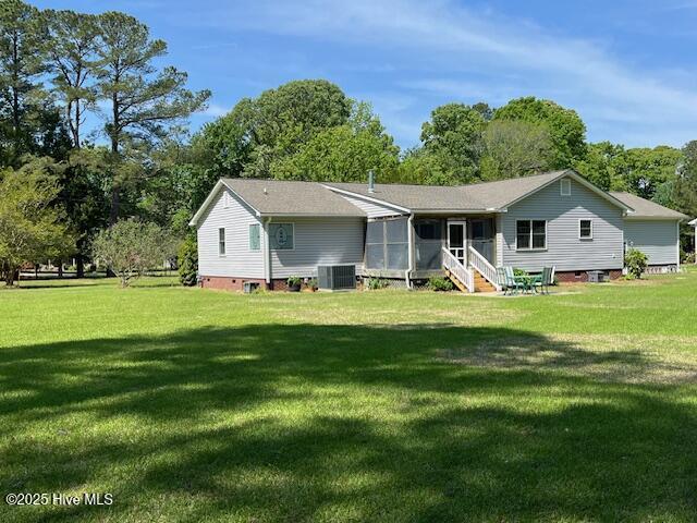 back of property with a lawn, central air condition unit, and a sunroom