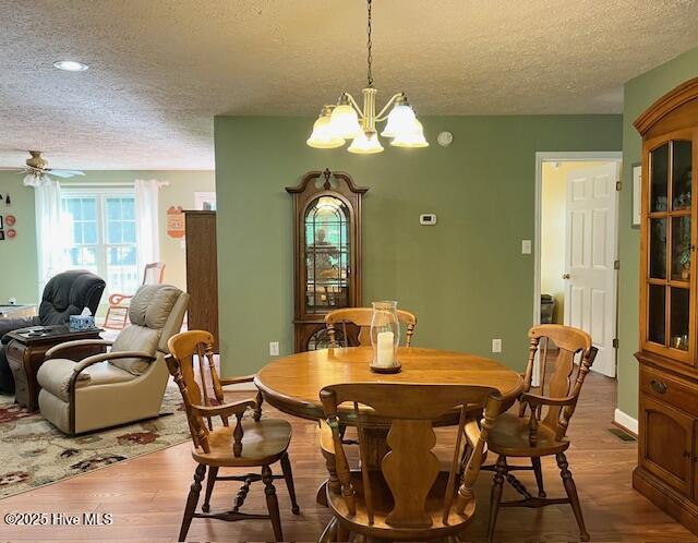 dining room with recessed lighting, a textured ceiling, ceiling fan with notable chandelier, and wood finished floors