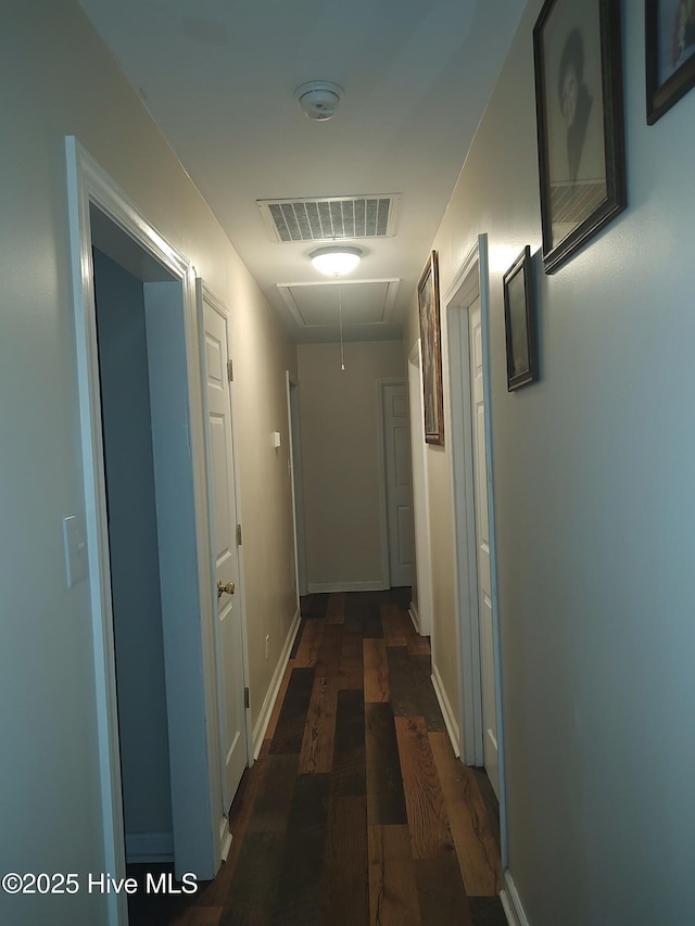 hall featuring attic access, wood finished floors, and baseboards