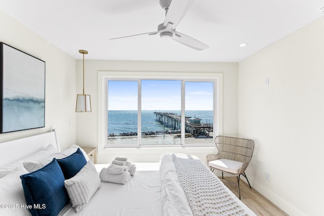 bedroom with a water view, wood finished floors, a ceiling fan, baseboards, and recessed lighting