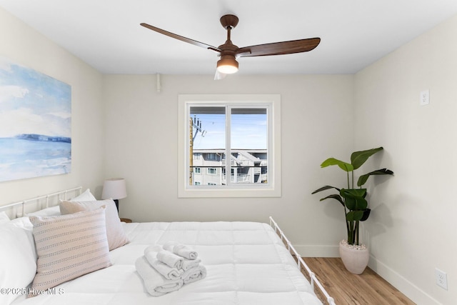 bedroom featuring wood finished floors, baseboards, and a ceiling fan