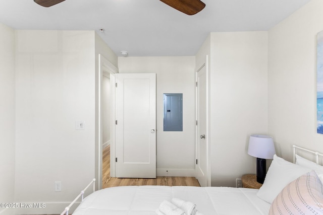 bedroom featuring electric panel, light wood finished floors, and baseboards