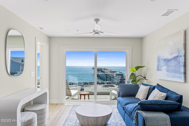 living room featuring a water view, wood finished floors, ceiling fan, and baseboards
