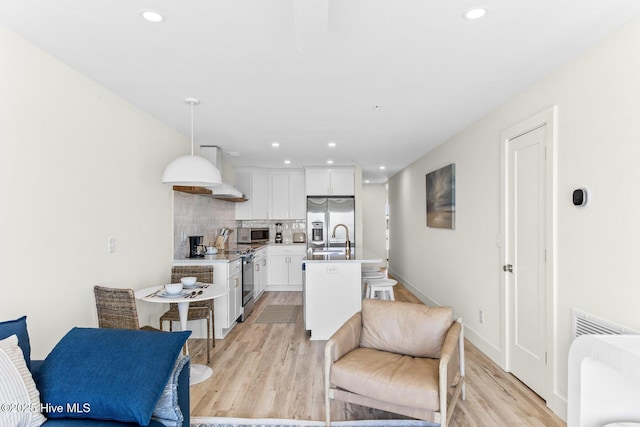 living area with light wood-type flooring, recessed lighting, and baseboards