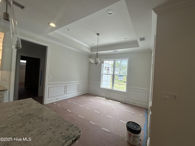 unfurnished dining area featuring a tray ceiling, a decorative wall, a chandelier, wainscoting, and recessed lighting