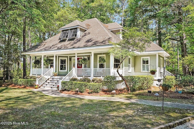country-style home with roof with shingles, a porch, and a front yard