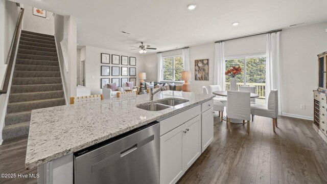 kitchen with white cabinets, dishwasher, a sink, dark wood-type flooring, and a kitchen island with sink