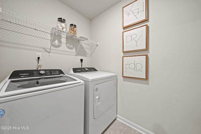 washroom with washing machine and clothes dryer, baseboards, marble finish floor, and laundry area