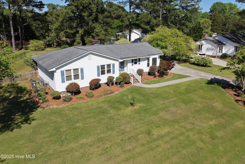 ranch-style home featuring roof with shingles, fence, and a front yard
