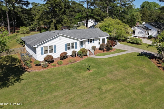 ranch-style home featuring roof with shingles, fence, and a front yard