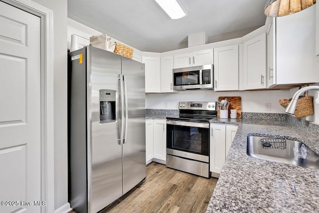 197 Cherry Rd, Southport, NC 28461 - kitchen with stainless steel appliances, a sink, light wood-style floors, and white cabinetry